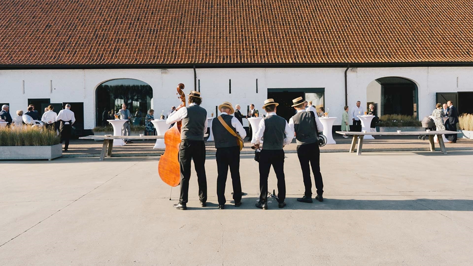 Muzikanten spelen voor een witgekalkte West-Vlaamse hoeve